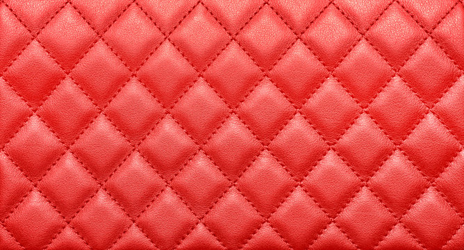Close-up texture of genuine leather with rhombic stitching. Saturated red color