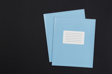 two notebooks on a black background, top view