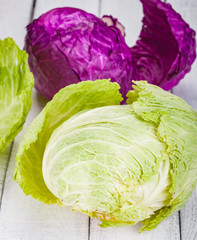 Green and red heads of cabbage on wooden background. Close up