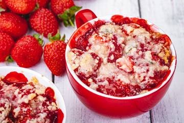 Strawberry crumble in cup on wooden rustic table. Close up