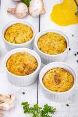 Polenta with mushrooms in white ramekin bowls on wooden rustic table. Close up