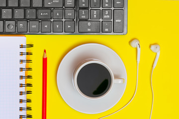 Workplace freelancer. Creative concept for creativity. Keyboard, notebook pencil, headphones, a cup of coffee, on a yellow background