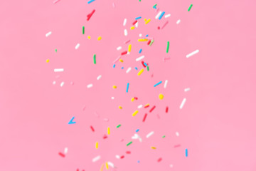 soaring down colorful sprinkles over pink background