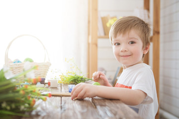 Boy decorate easter egg. A little boy painting and decorating Easter eggs. Portrait of cute boy 3 years old. He holds brush and paints Easter eggs