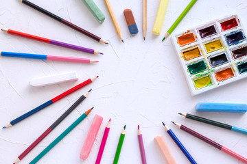 Naklejka premium Watercolor paints for drawing and pencils with chalk on a white table.arranged in a circle