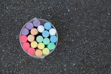 Top view of new colorful chalks outdoors isolated on surface of grey grunge pavement as background. Horizontal color photography.