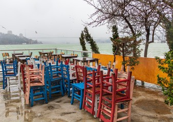 Wet wooden tables and colorful chairs under the rain. Istanbul