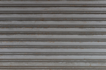 A closeup shot of automatic metal roller door used in factory, storage, garage, and industrial warehouse. The corrugated and foldable metal sheet offer space saving and provide urban and rustic feel