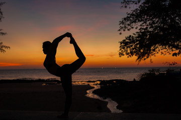 woman  silhouette playing yoga on sunset background in Thailand