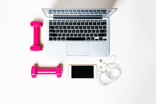 Flat Lay To Composition With Fitness Equipment Pink Dumbbels, Computer, Mobile Phone, Headphones And Space For Text On White Background. Sport, Office, Lifestyle Concept . Copy Space, Top View.