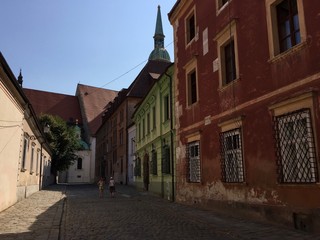 Fototapeta na wymiar Cobblestone covered street and colourful houses in Bratislava's medieval old town in Slovakia. St. Martin's Cathedral can be seen in the background.