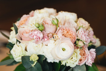 wedding rings on a background of flowers of a gentle wedding bouquet, selective focus