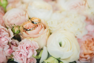 wedding rings on a background of flowers of a gentle wedding bouquet, selective focus