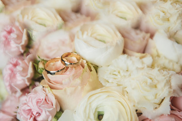 wedding rings on a background of flowers of a gentle wedding bouquet, selective focus