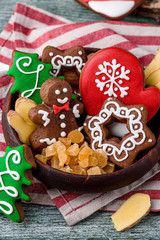 Gingerbread mitten, little man, snowflakes, christmas trees in a brown wooden plate on a striped napkin on a green wooden background. close up. space