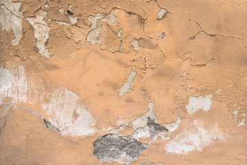 Peeling paint on a dilapidated house wall with cracks