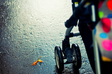 Walk with baby in stroller in autumn in the rain. Detail stroller wheel.