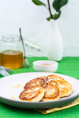 Homemade cottage cheese pancakes with honey on a plate on a wooden table