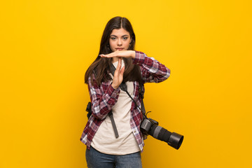 Photographer teenager girl over yellow wall making time out gesture
