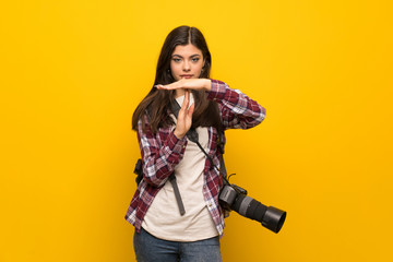 Fototapeta na wymiar Photographer teenager girl over yellow wall making time out gesture