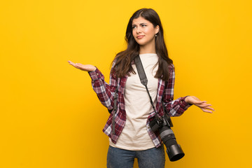 Photographer teenager girl over yellow wall unhappy because not understand something