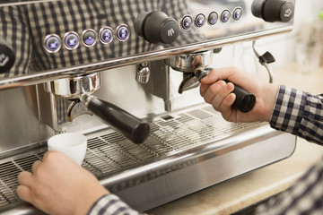 Cropped close up of a professional barista using coffee machine while working at his cafe preparing drinks for clients equipment profession small business occupation entrepreneur worker beverage