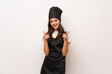 Teenager chef  over white wall pointing to the front and smiling