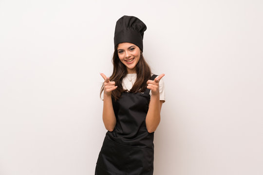 Teenager chef  over white wall pointing to the front and smiling