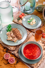 National Russian and Ukrainian dishes: borscht, buckwheat with stewed mushrooms and Russian salad in gray plates on wooden boards in rustic composition. close-up. top view