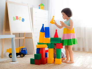 Happy preschool children play with toy blocks.