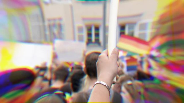 Rear view of large crowd of people with enthusiastic male holding rainbow flags at annual pride gays and lesbians parade marching French streets dancing fun party atmosphere rgb displacement effect