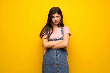 Teenager girl over yellow wall feeling upset