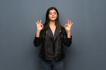 Teenager girl over grey wall in zen pose