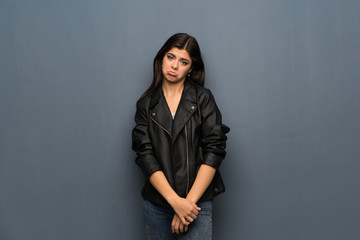 Teenager girl over grey wall with sad and depressed expression