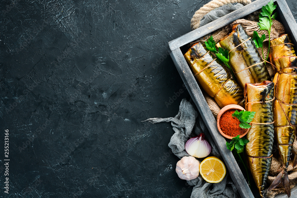 Wall mural Smoked fish mackerel in a wooden box. Top view. Free space for your text.