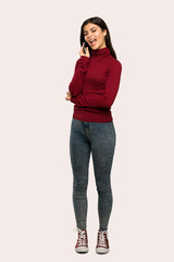 A full-length shot of a Teenager girl with turtleneck keeping a conversation with the mobile phone over isolated background