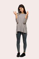 A full-length shot of a Teenager girl with striped shirt making money gesture over isolated background