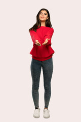 A full-length shot of a Teenager girl with red sweater holding copyspace imaginary on the palm to...