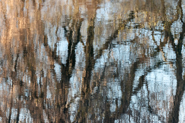 Obraz premium Blurred water reflections of autumn trees with waves and ripples. Abstract pattern artistic background.