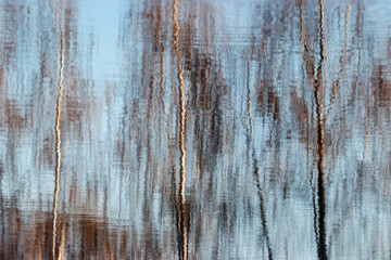 Obraz premium Blurred water reflections of autumn trees with waves and ripples. Abstract pattern artistic background.