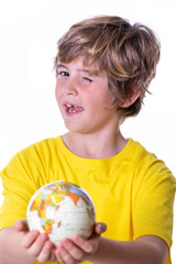 Young boy with yellow T-shirt, aviator goggles, plane and world ball smiling