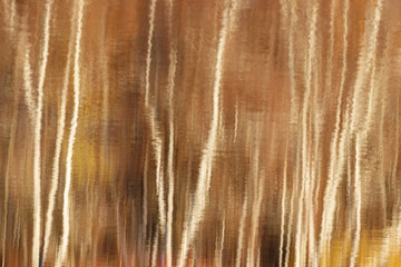 Blurred water reflections of autumn trees with waves and ripples. Abstract pattern artistic background.