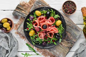 Salad with Prosciutto, olives and arugula. Cold snacks. Top view. Free space for your text.