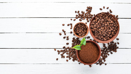 Ground coffee and coffee beans. On a white wooden background. Top view. Free space for your text.