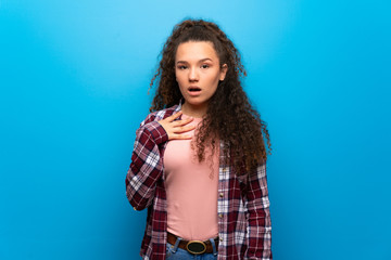 Teenager girl over blue wall surprised and shocked while looking right