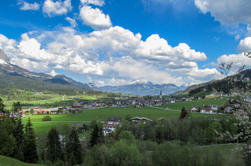 Fototapeta na wymiar Panorama from the village of Elmau -Tyrol near the city of Innsbruck with green sunny Austrian Alps in Tyrol with snowy mountains in the background under blue sky