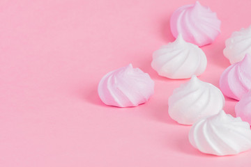 Obraz na płótnie Canvas White and pink twisted meringues on pink background. French dessert prepared from whipped with sugar and baked egg whites. Greeting card with copy space