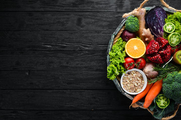 Fresh vegetables and fruits in a wooden box on a black background. Organic food. Top view. Free copy space.