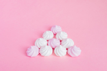 white and pink twisted meringues in a shape of pyramid on pink background, greeting card, copy space