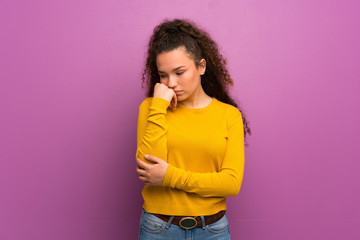 Teenager girl over purple wall having doubts